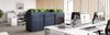 Bisley Glide Cupboard With Two Door Perforated Front Unit In White Finish With Indoor Plant And Desk In Office Setting