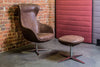 Loop Upholstered Lounge Armchair In Brown Finish With 4 Star Base Footrest And Upholstered Greestanding Screen In Studio Setting