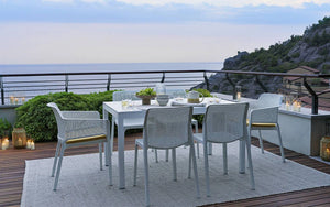 Nardi Net Stackable Monobloc Armchair in White with White Rectangular Table Overlooking the Ocean