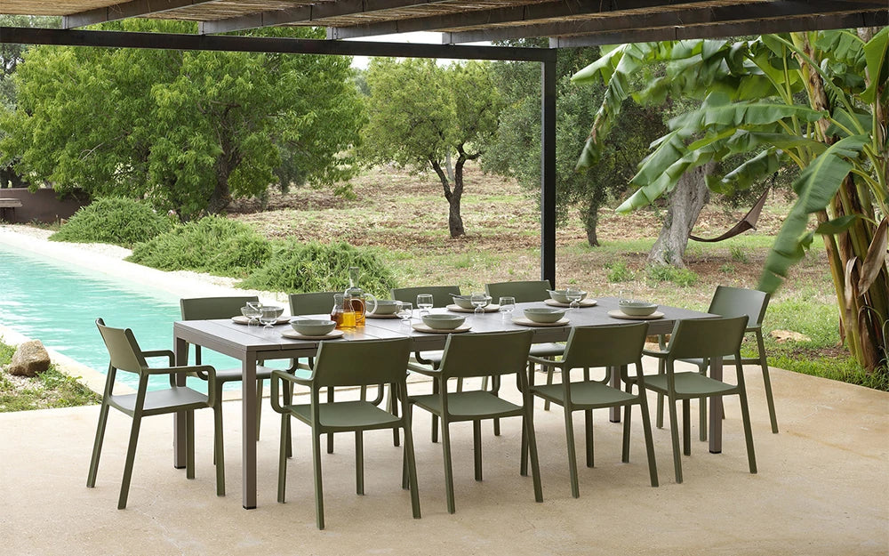 Nardi Thrill Stackable Monobloc Chair with Armrest in Green with Long Table Beside Swimming Pool Area