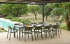 Nardi Thrill Stackable Monobloc Chair with Armrest in Green with Long Table Beside Swimming Pool Area