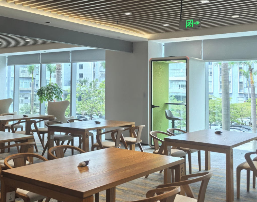 Zum Phonebooth in White Finish with Wooden Tables and Chairs in Canteen Setting